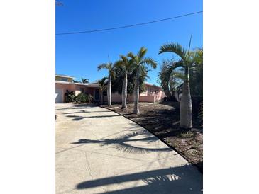Charming single-story home with a vibrant pink exterior and a well-maintained front yard with mature palm trees at 3800 Belle Vista E Dr, St Pete Beach, FL 33706