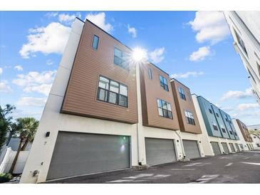 Modern townhome row featuring two-car garages, neutral exteriors and ample natural light against blue sky at 4810 W Mcelroy Ave # 7, Tampa, FL 33611