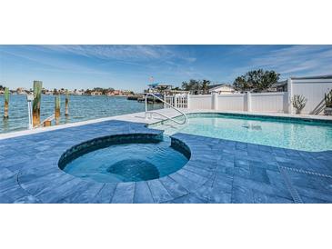 Waterfront pool and spa area with blue tile, white fencing, and dock access at 629 59Th Ave, St Pete Beach, FL 33706