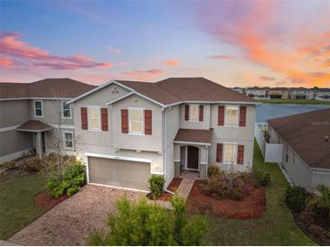 Charming two-story home featuring a brick driveway, two-car garage, and manicured landscaping at sunset at 11544 Brighton Knoll Loop, Riverview, FL 33579