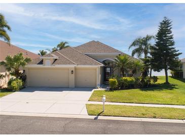Charming home featuring a well-manicured lawn, a spacious three-car garage and beautiful landscaping at 1648 Mira Lago Cir, Ruskin, FL 33570