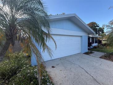 Attached two-car garage in a light-blue home with mature landscaping and a white garage door at 1982 Seton Dr, Clearwater, FL 33763