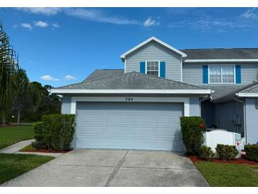 Charming home featuring a two-car garage, complemented by well-maintained landscaping and bright blue shutters at 284 Hemingway Dr, Oldsmar, FL 34677