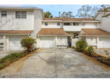 Charming townhome featuring white siding, a brown roof, attached garage and a well-maintained driveway at 5203 Bayshore Blvd # 5, Tampa, FL 33611