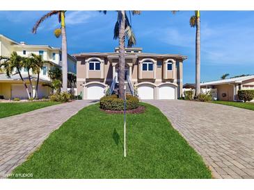 Beige home featuring dual garages, staircase, and tropical landscaping at 750 123Rd Ave, Treasure Island, FL 33706