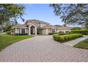 Elegant home with red tile roof, arched entryway, paver driveway, and manicured landscaping in a suburban setting at 7888 Lantana Creek Rd, Seminole, FL 33777