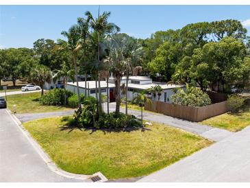 A modern home with a flat roof, a red door, a circular driveway, and mature palm trees at 7990 42Nd N St, Pinellas Park, FL 33781