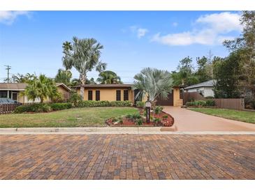 Charming single story home with beautiful landscaping, mature palm trees, and a brick paved circular driveway at 1787 Pasadena Dr, Dunedin, FL 34698