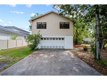 Two-story home showcasing a two-car garage with a long driveway and well-maintained landscaping at 9811 Memorial Hwy, Tampa, FL 33615