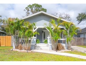 Charming home featuring mature palms, a gray exterior, a welcoming front porch, and a well-manicured lawn at 311 W Chelsea St, Tampa, FL 33603