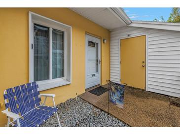 Inviting yellow home with a white trimmed window and an open door that is number 67D with a blue chair at 3710 41St S Way # D, St Petersburg, FL 33711
