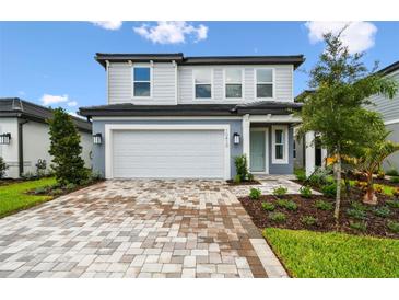 Charming two-story home showcasing a well-manicured lawn and a driveway paved with decorative brick at 10410 Cross River Trl, Parrish, FL 34219
