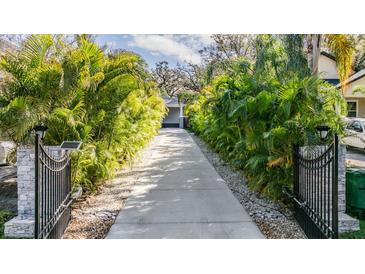 Long driveway lined with lush tropical foliage leading to a charming home at 6911 N 19Th St, Tampa, FL 33610