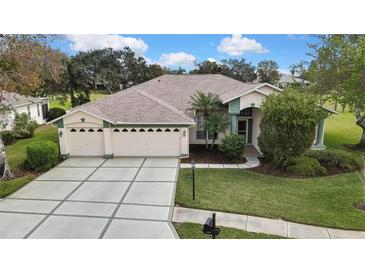 Charming single-story home featuring a three-car garage, lush landscaping, and a well-maintained lawn at 18951 Grand Club Dr, Hudson, FL 34667