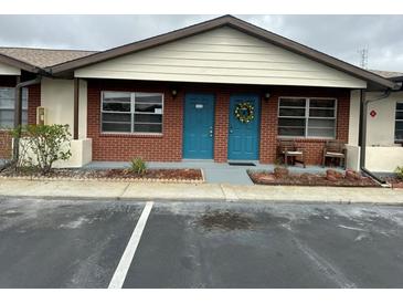 Cozy brick condo featuring a blue front door with a festive wreath and well-maintained landscaping at 24862 Us Highway 19 N # 1504, Clearwater, FL 33763