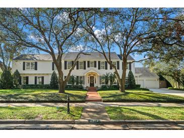 Stately white home framed by mature trees and lush landscaping. Brick walkway leads to the front entrance at 3412 W Mckay Ave, Tampa, FL 33609