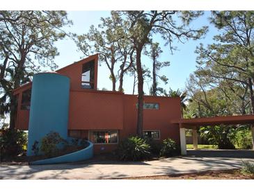 Unique home featuring a modern design, a cylindrical tower, and a convenient carport, all surrounded by mature trees at 7219 Williams S Dr, St Petersburg, FL 33705