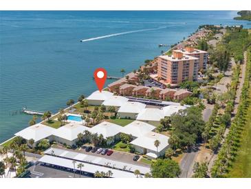 Waterfront condo complex featuring community pool, boat dock, and manicured landscaping near the bay at 7310 Sunshine Skyway S Ln # 219, St Petersburg, FL 33711