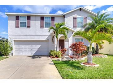 Charming two-story home with a well-manicured lawn, lush tropical landscaping, and a two-car garage at 15410 Fire Rock Pl, Ruskin, FL 33573