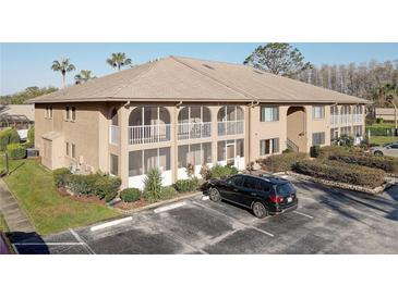 Beige two-story condo building featuring a large screened balcony and well-maintained landscaping at 3200 Charter Club Dr # A1, Tarpon Springs, FL 34688