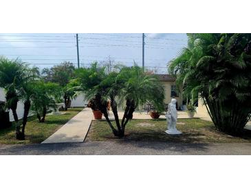 Charming front yard adorned with lush palms, potted plants, and decorative statues at 6213 Sheldon Rd, Tampa, FL 33615