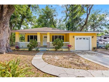 Charming yellow home with a covered porch, stone accents, and a well-manicured lawn at 3908 Alafia Blvd, Brandon, FL 33511