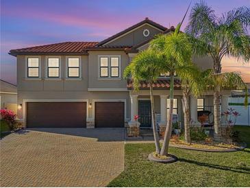 Two-story home boasting a tile roof, lush landscaping, three-car garage, and inviting curb appeal at 11965 Cinnamon Fern Dr, Riverview, FL 33579