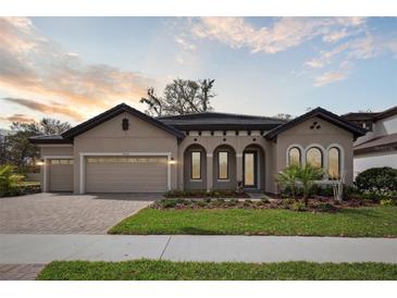 Stunning single-story home featuring a well-manicured lawn, arched windows and doorway, and a spacious three-car garage at 4535 Foley Grove Dr, Valrico, FL 33596