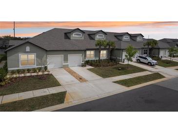 Charming townhome exterior featuring a two-car garage, well-maintained lawn and beautiful landscaping at 6850 Ripple Pond Loop, Zephyrhills, FL 33541