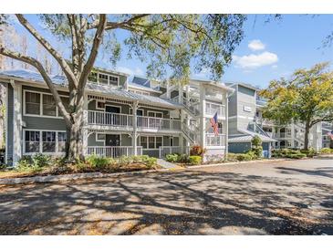 Condominium complex with multiple floors, white railings, and a well-maintained landscaped yard at 2511 Dolly Bay Dr # 304, Palm Harbor, FL 34684