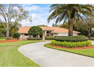 Single-story home with a circular driveway, tile roof, lush landscaping, and a welcoming entrance at 30 Stanton Cir, Oldsmar, FL 34677