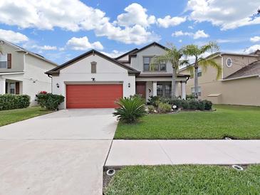 Charming two-story home with well-manicured lawn, beautiful landscaping and a red two car garage door at 4136 Shrewbury Pl, Land O Lakes, FL 34638