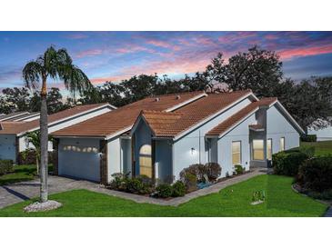 Charming single-story home featuring a tile roof, lush landscaping, and a well-maintained lawn at 5839 Garden Lakes Dr, Bradenton, FL 34203