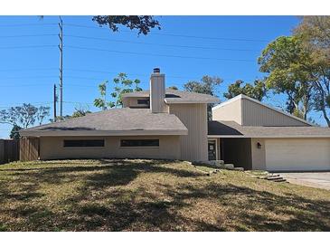 Contemporary exterior with neutral siding, chimney, and a two-car garage showcases modern architecture and curb appeal at 70 Durham Ct, Palm Harbor, FL 34683