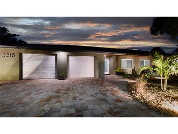 Charming home featuring a well-manicured front yard and a brick driveway leading to a two-car garage, shot at twilight at 2215 River Ridge Dr, Sarasota, FL 34239