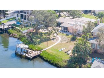 Waterfront property featuring a private dock, lush landscaping, and screened-in porch overlooking the tranquil canal at 4907 W Spring Lake Dr, Tampa, FL 33629
