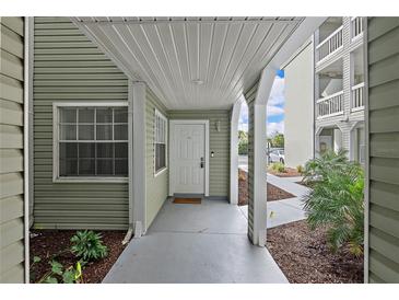 Inviting entrance with sage green siding, decorative columns, and a neutral-colored walkway at 6916 Stones Throw N Cir # 9110, St Petersburg, FL 33710