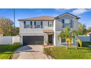 Charming two-story home featuring a well-manicured lawn, mature palms, a two-car garage, and a welcoming front entrance at 7112 Samuel Ivy Dr, Tampa, FL 33619