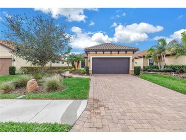 Inviting home featuring a tile roof, paver driveway, two car garage, and lush landscaping at 10446 Highland Park Pl, Palmetto, FL 34221