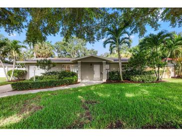 Charming single-story home featuring lush landscaping, a well-manicured lawn, and a welcoming front entrance at 1180 Eden Isle Ne Blvd, St Petersburg, FL 33704
