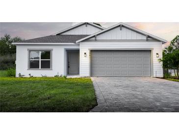 Charming one-story home with a gray brick driveway, an attached two car garage, and manicured lawn at 134 Jade St, Rotonda West, FL 33947