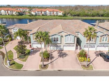 Aerial view of townhomes with garages and well-maintained landscaping near a waterfront at 1524 Lago Vista Blvd, Palm Harbor, FL 34685