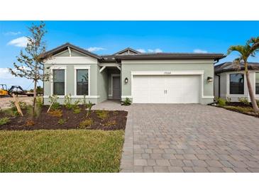 Charming single Gathering home with a light green exterior and a well-maintained paver driveway at 17069 Moonflower Dr, Venice, FL 34293