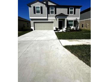 Charming two-story home with gray siding, a well-manicured lawn, and a concrete driveway at 2359 Lanier Rd, Zephyrhills, FL 33541