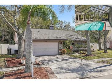 Charming single-story home with a stone-accented facade, mature landscaping, and a screened-in pool visible in the background at 12030 Steppingstone Blvd, Tampa, FL 33635