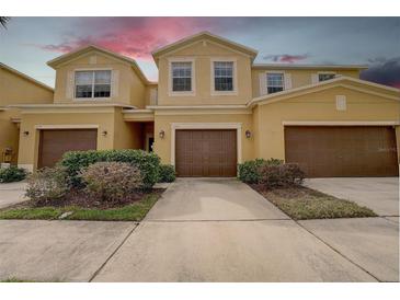 Inviting exterior view of the townhome featuring a two-car garage, well-maintained landscaping, and a neutral color palette at 2007 Hawks View Dr, Ruskin, FL 33570
