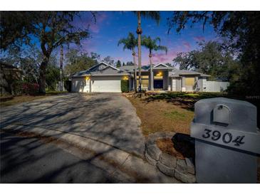 Charming single Gathering home featuring a paved driveway, mature trees and tropical landscaping at 3904 Executive Cir, Plant City, FL 33566
