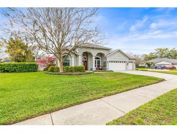 Charming single-story home with a well-manicured lawn, mature landscaping, and a three-car garage at 17138 Downs Dr, Odessa, FL 33556