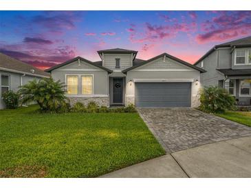 Charming single Gathering home boasting a 2-car garage, manicured lawn, and welcoming stone accents at 34303 Radley Way, Wesley Chapel, FL 33545