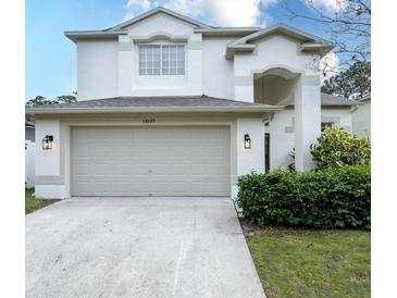 Charming two-story home featuring an attached two car garage and well-maintained landscaping at 13225 Royal George Ave, Odessa, FL 33556